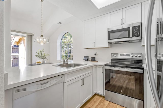 kitchen featuring white cabinets, stainless steel appliances, vaulted ceiling, and decorative light fixtures