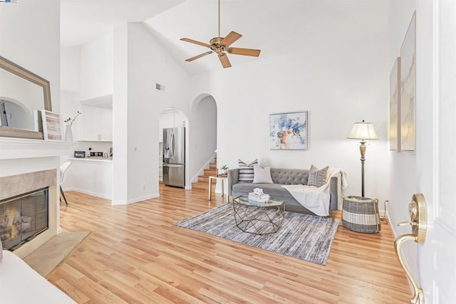 living room with light wood-type flooring, high vaulted ceiling, and ceiling fan