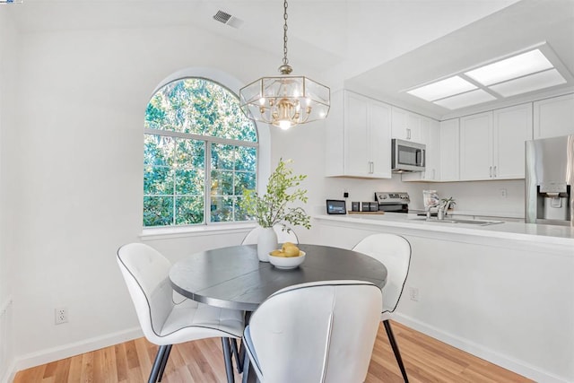 dining space with sink, light hardwood / wood-style floors, plenty of natural light, and lofted ceiling