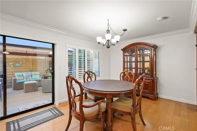 dining room featuring crown molding, light wood-type flooring, and a notable chandelier