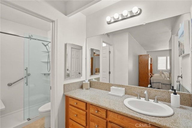 bathroom featuring toilet, a shower with shower door, and vanity