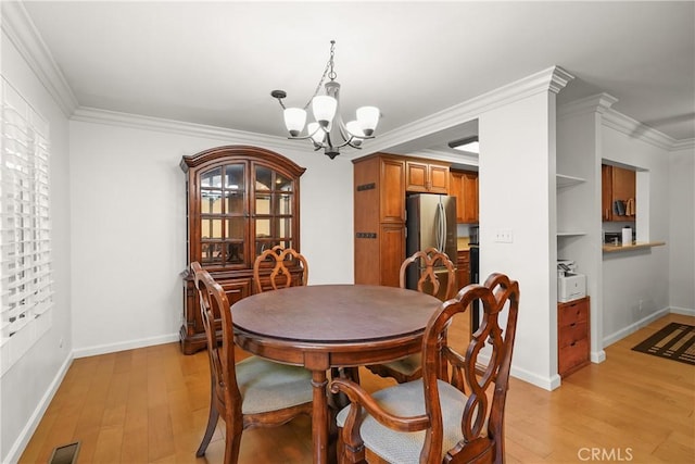 dining room featuring light hardwood / wood-style floors, crown molding, and a chandelier