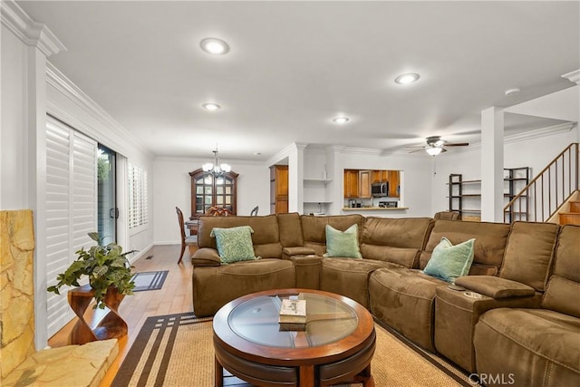 living room with light hardwood / wood-style floors, ornamental molding, and ceiling fan with notable chandelier