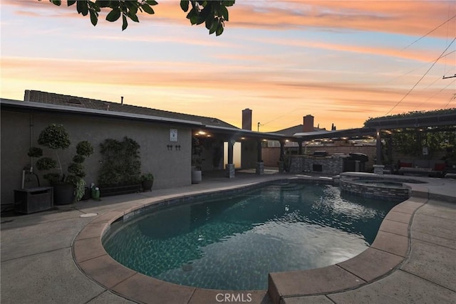 pool at dusk with an in ground hot tub and a patio