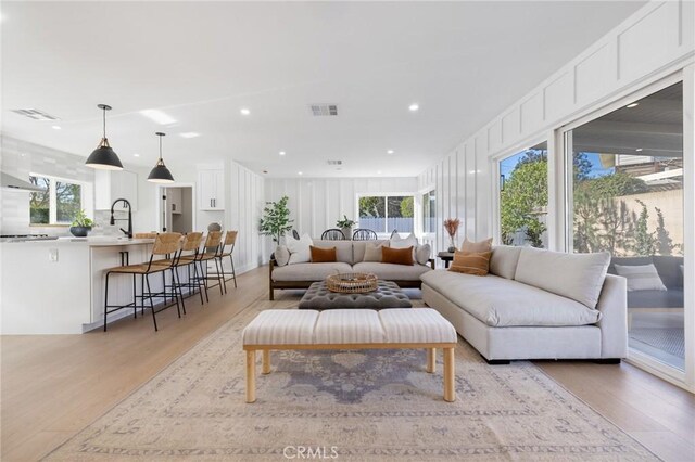 living room with a healthy amount of sunlight, sink, and light hardwood / wood-style floors