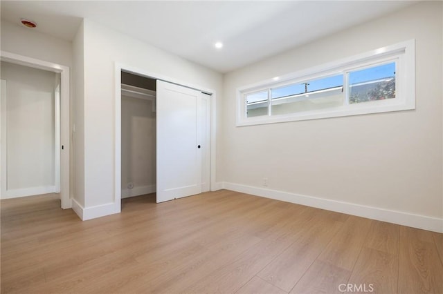 unfurnished bedroom with a closet and light hardwood / wood-style flooring