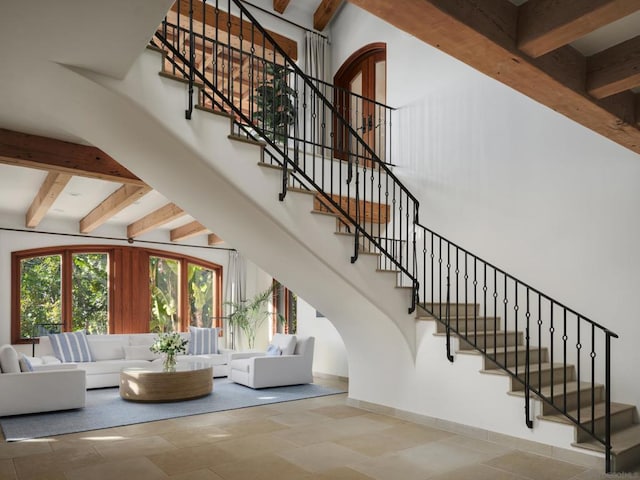 stairway with beamed ceiling and a high ceiling