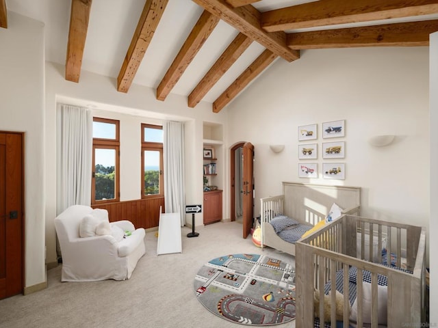 bedroom with lofted ceiling with beams, a nursery area, and light colored carpet