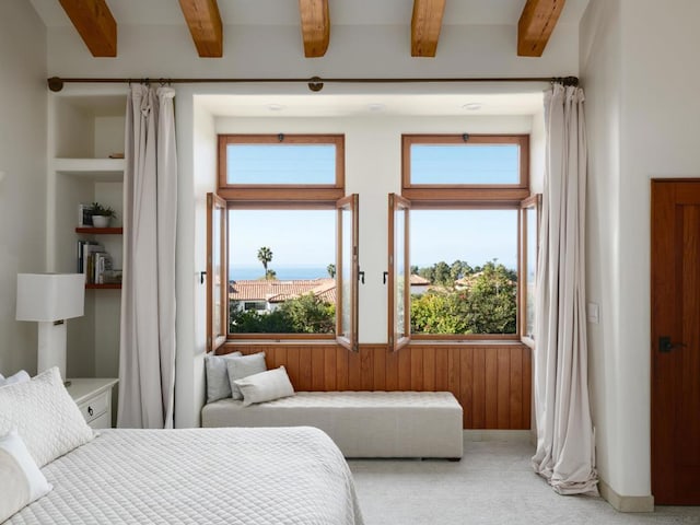 carpeted bedroom with beam ceiling and wooden walls