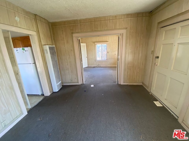 hall with wooden walls and a textured ceiling