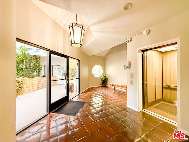 doorway with a chandelier, vaulted ceiling, french doors, and dark tile patterned floors