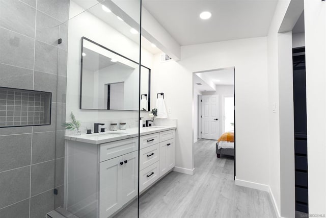 bathroom with wood-type flooring, vanity, and walk in shower