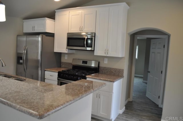 kitchen with appliances with stainless steel finishes, white cabinetry, sink, dark hardwood / wood-style floors, and light stone counters