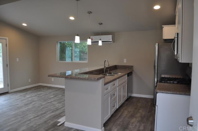 kitchen with white cabinetry, hanging light fixtures, sink, kitchen peninsula, and dark stone counters