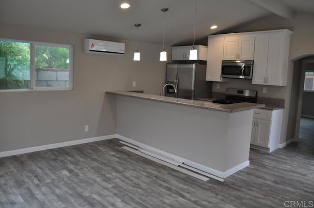 kitchen with dark stone counters, white cabinets, pendant lighting, a wall unit AC, and stainless steel appliances