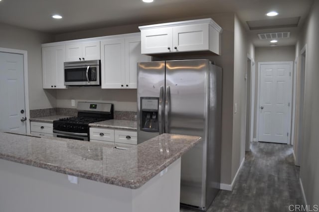 kitchen featuring white cabinets, light stone counters, appliances with stainless steel finishes, and dark wood-type flooring