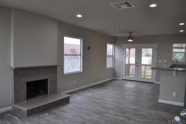 unfurnished living room with dark hardwood / wood-style floors, a premium fireplace, a wealth of natural light, and french doors