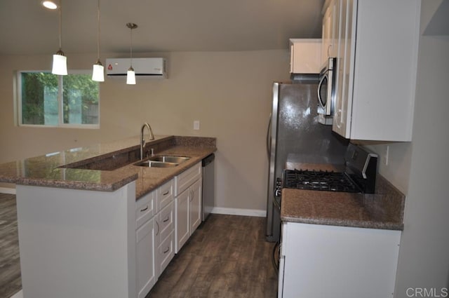 kitchen featuring an AC wall unit, white cabinets, sink, hanging light fixtures, and kitchen peninsula