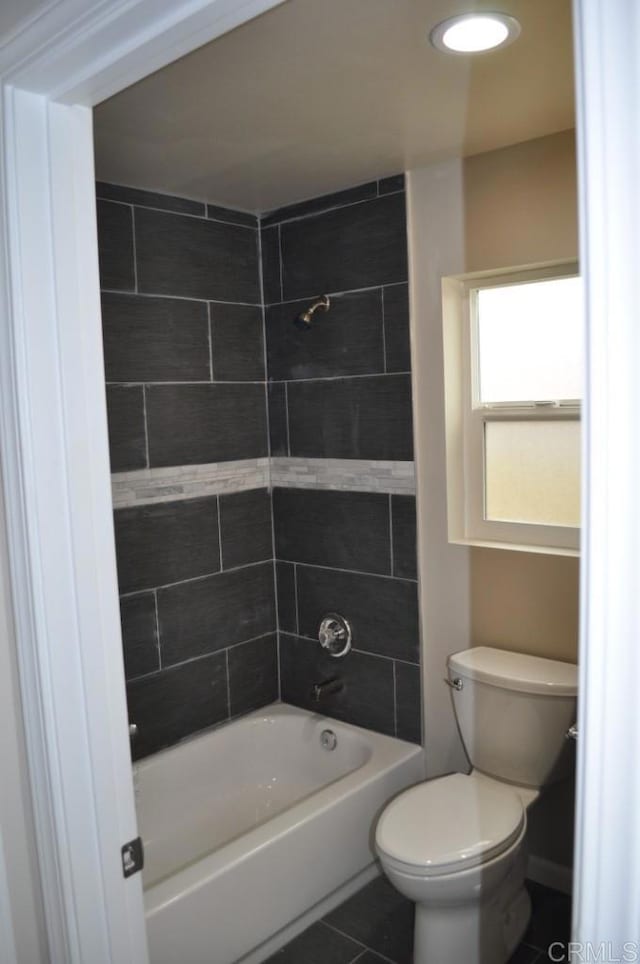 bathroom featuring toilet, tiled shower / bath, and tile patterned flooring