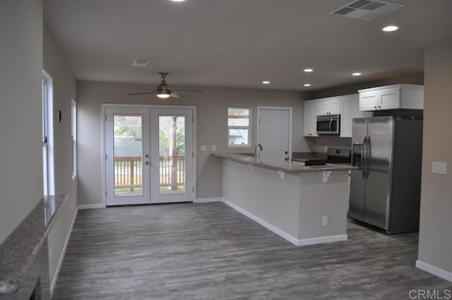 kitchen with kitchen peninsula, french doors, appliances with stainless steel finishes, white cabinetry, and light stone counters