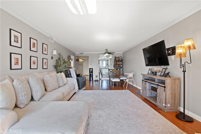 living room with hardwood / wood-style floors, crown molding, and ceiling fan