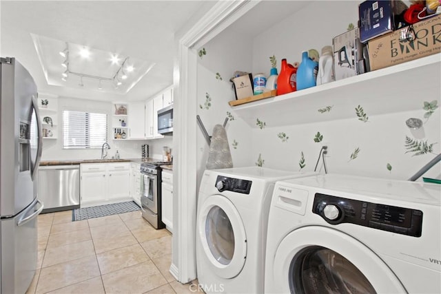 clothes washing area featuring light tile patterned floors, sink, and washer and dryer