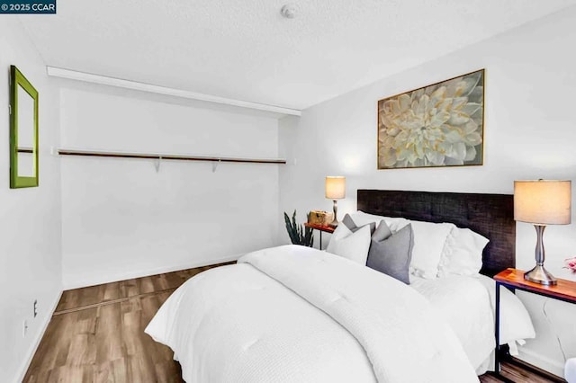 bedroom with hardwood / wood-style floors and a textured ceiling