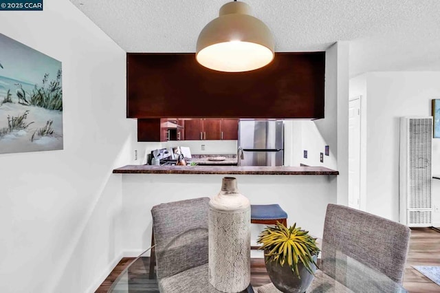 kitchen with stainless steel appliances, kitchen peninsula, dark hardwood / wood-style floors, and a textured ceiling