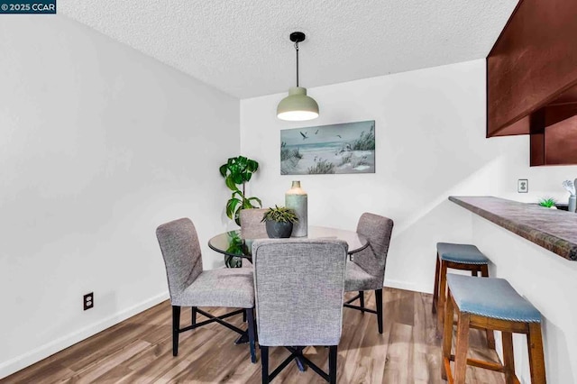 dining room featuring wood-type flooring and a textured ceiling