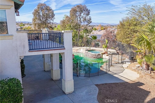 view of patio / terrace with a pool with hot tub and a mountain view