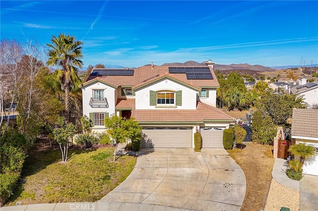 mediterranean / spanish house featuring a garage, a mountain view, a front yard, and solar panels