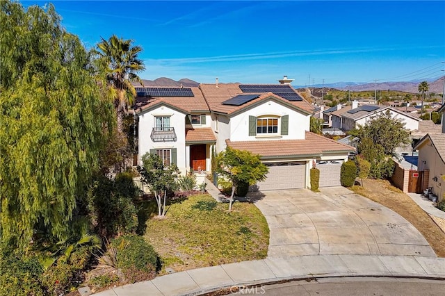 view of front of home featuring a garage, a front lawn, and solar panels