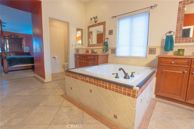 bathroom with vanity, tiled tub, tile patterned floors, and toilet