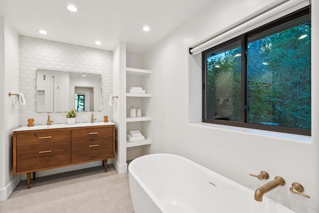 bathroom featuring vanity, a tub to relax in, plenty of natural light, and built in shelves