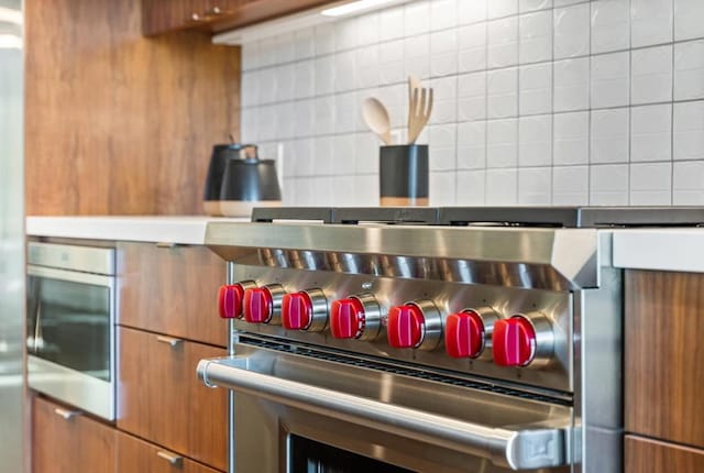 interior details with decorative backsplash and appliances with stainless steel finishes