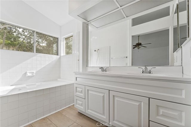 bathroom with ceiling fan, tiled tub, vanity, and tile patterned flooring