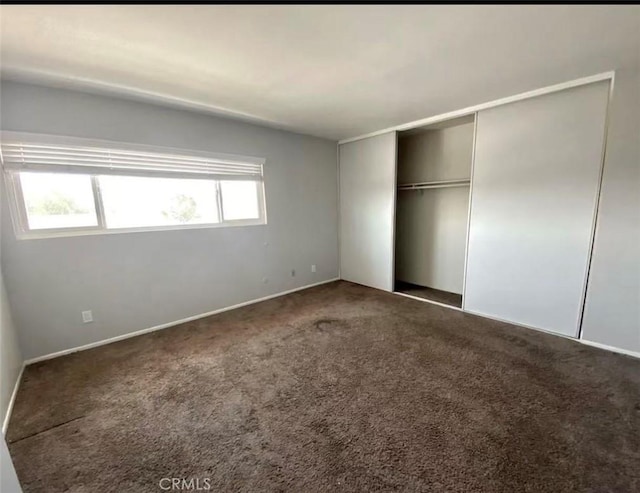 unfurnished bedroom with dark carpet and a closet