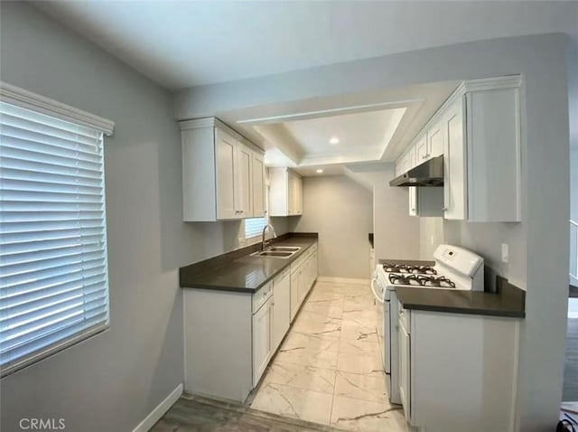 kitchen with a raised ceiling, white cabinetry, sink, and white gas stove