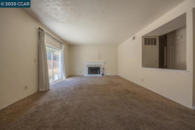 unfurnished living room with a textured ceiling, carpet floors, and a high end fireplace