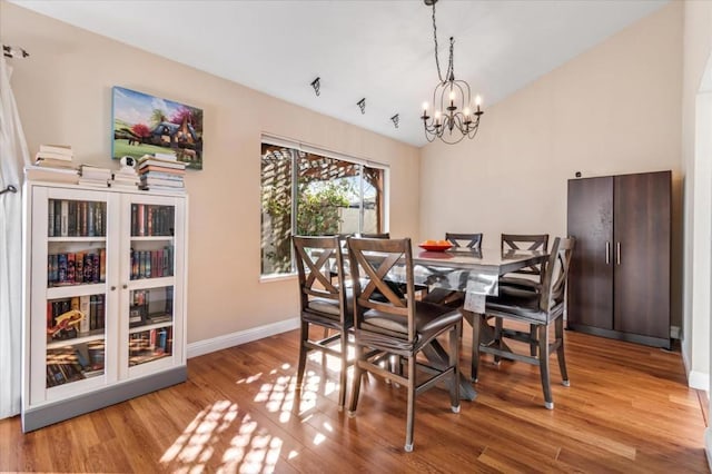 dining space with hardwood / wood-style floors and an inviting chandelier