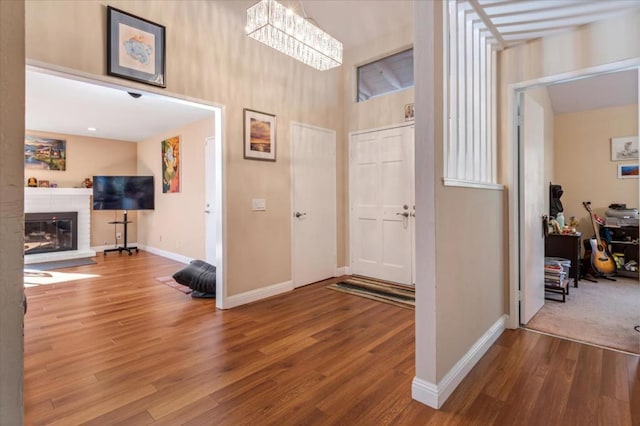 foyer with a brick fireplace, wood-type flooring, and an inviting chandelier