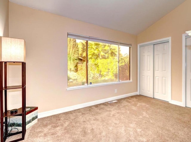 unfurnished bedroom with a closet, vaulted ceiling, and light colored carpet