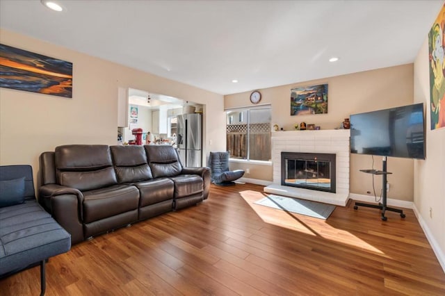 living room featuring a brick fireplace and wood-type flooring