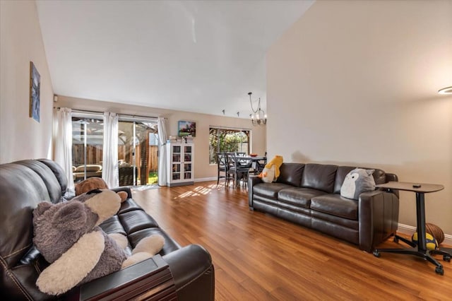 living room with hardwood / wood-style floors, lofted ceiling, and a notable chandelier