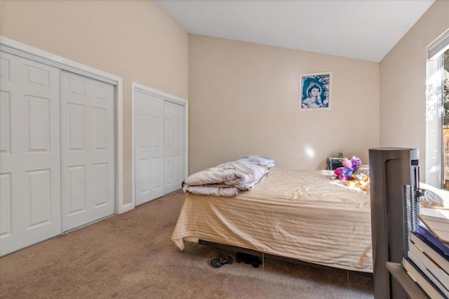 bedroom with carpet floors, vaulted ceiling, and multiple closets