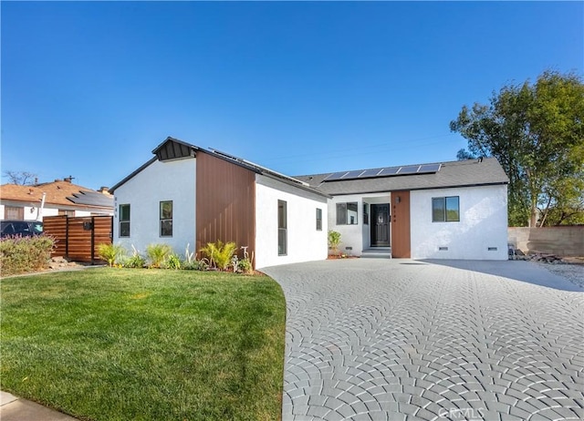 rear view of house with a yard and solar panels