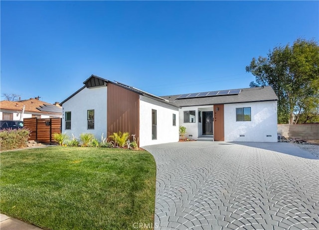 back of property with a lawn and solar panels