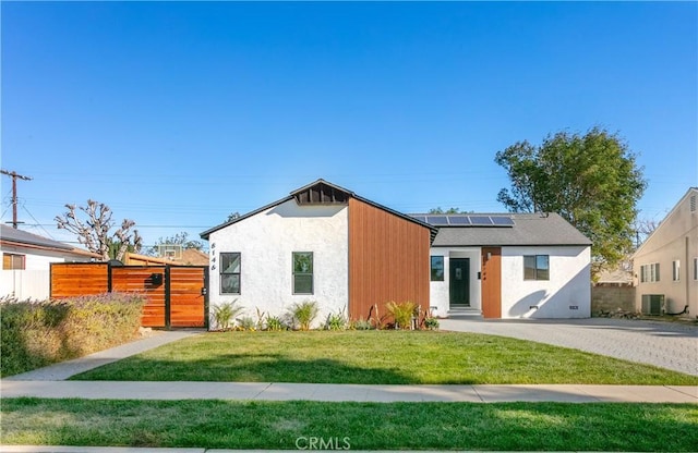 view of front facade featuring central AC, a front yard, and solar panels