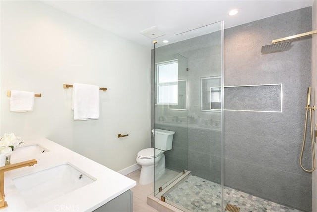 bathroom with vanity, toilet, tiled shower, and tile patterned flooring