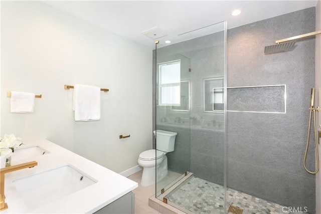 bathroom with vanity, toilet, and a tile shower